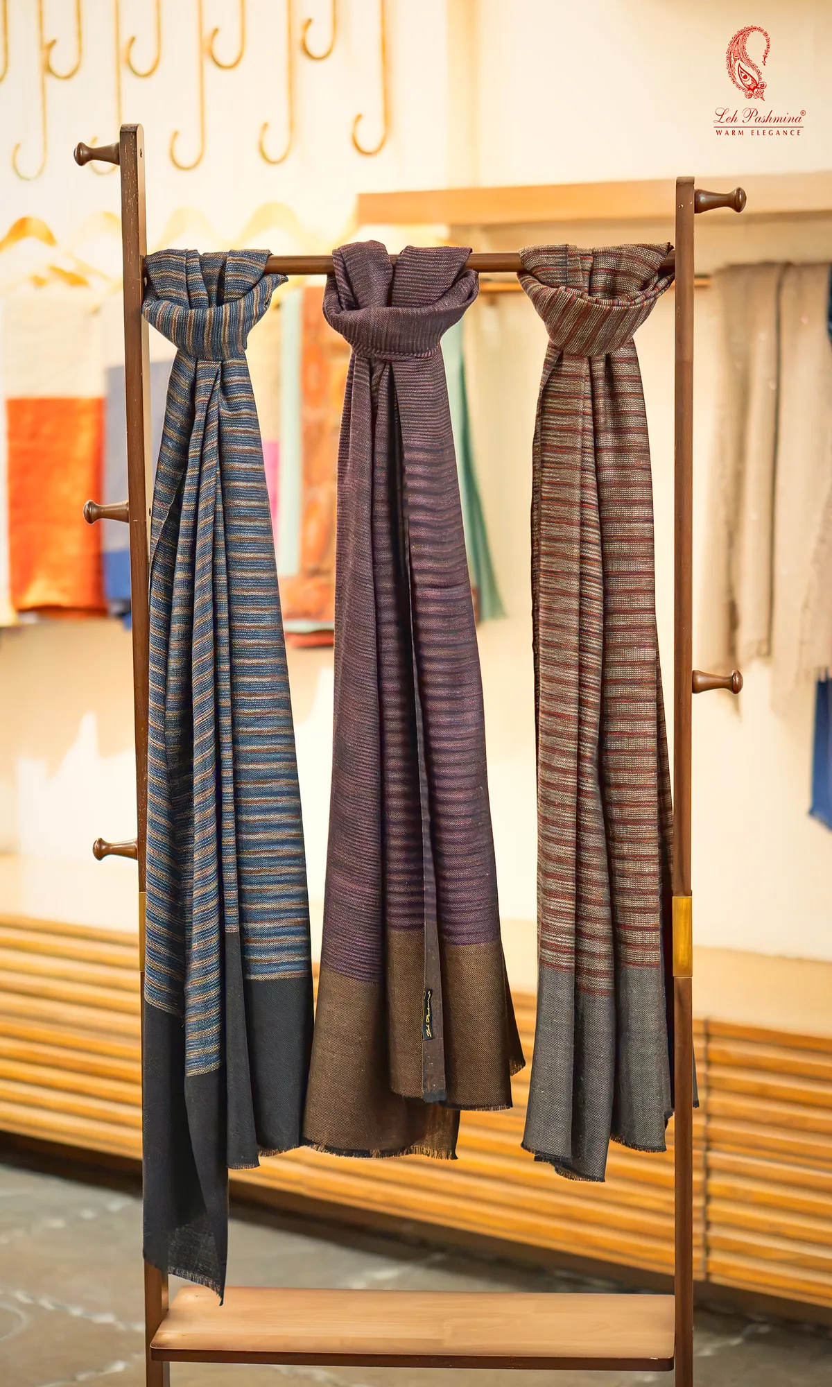 Three striped stoles on a wooden rack in the Leh Pashmina showroom, Ghaziabad